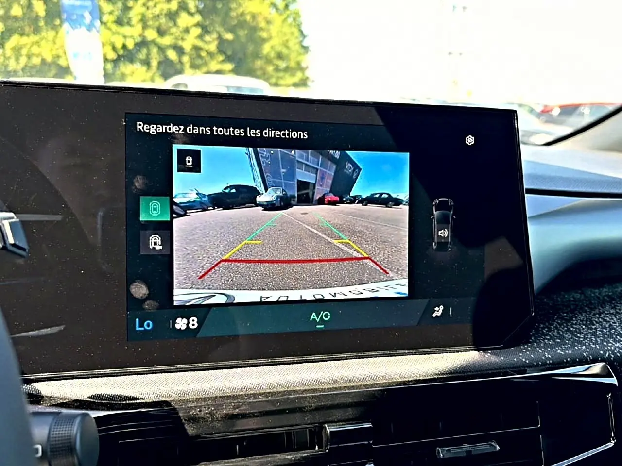 Écran tactile intérieur montrant la caméra de recul d'une Renault Clio VI noire, vue depuis le poste de conduite.