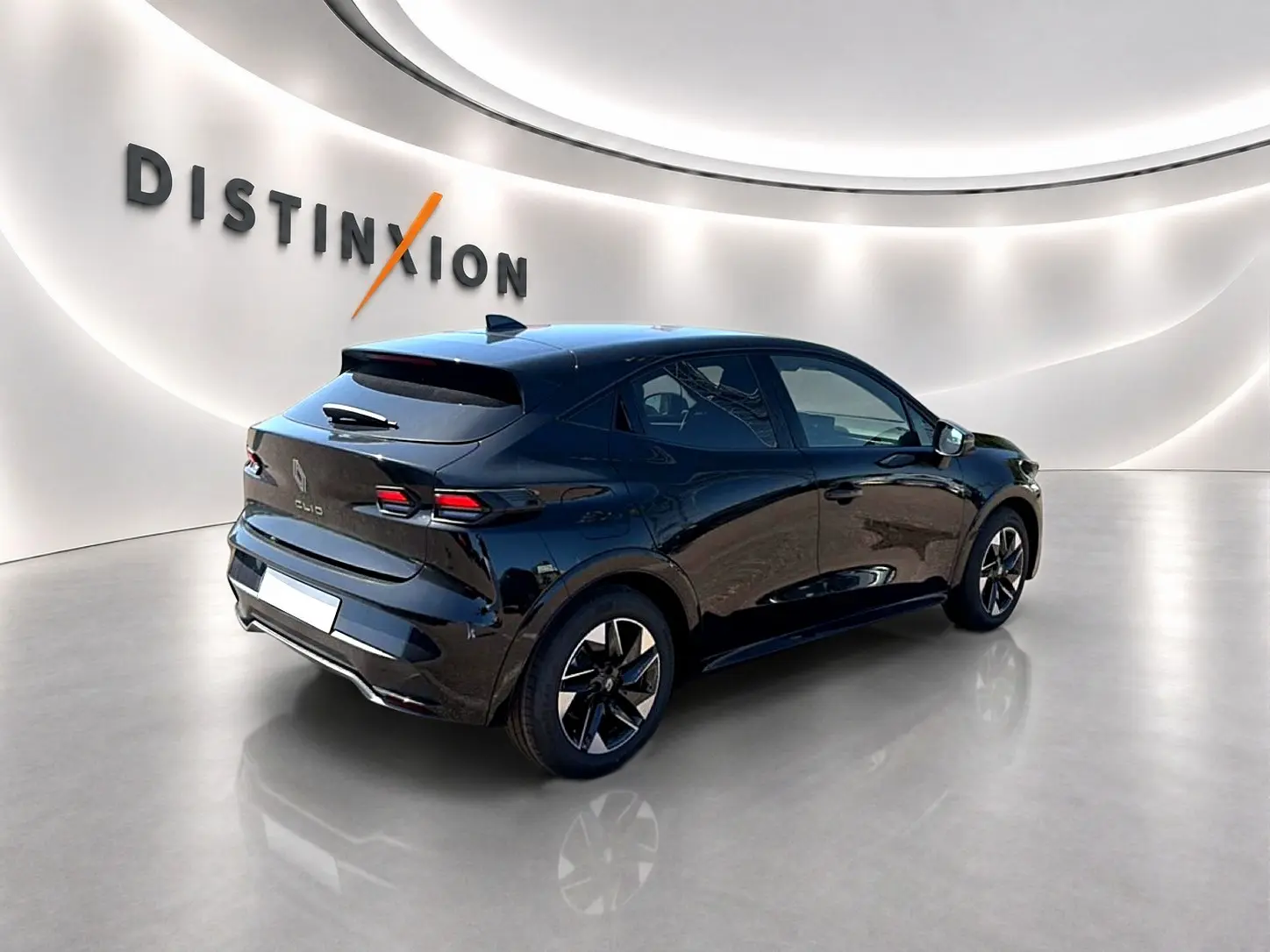 Renault Clio VI noire vue en 3/4 arrière droit dans un showroom lumineux avec jantes alu distinctives.
