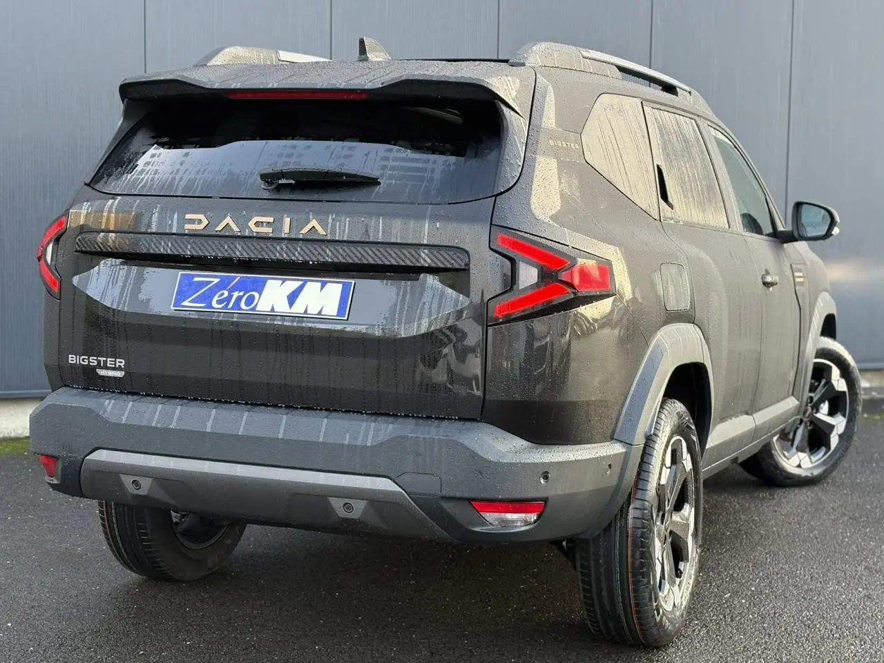 Vue 3/4 arrière droite du Dacia Bigster noir nacré avec feux arrière en forme de flèche et jantes alliage noires.