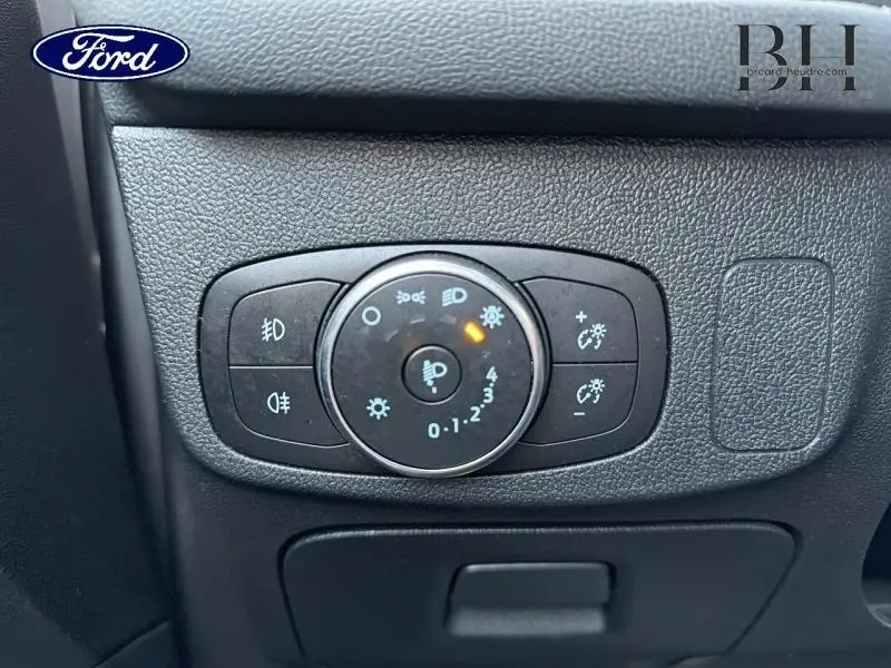 Gros plan sur la commande d’éclairage noire du tableau de bord de la Ford Focus gris lunaire métallisé, avec témoin orange allumé.