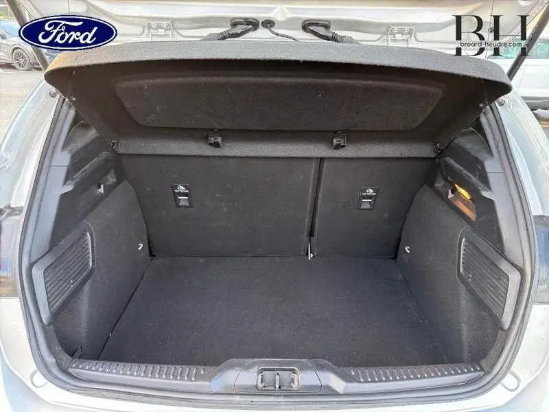 Coffre ouvert vu de l'arrière d'une Ford Focus gris lunaire métallisé, montrant un espace de chargement propre et spacieux.