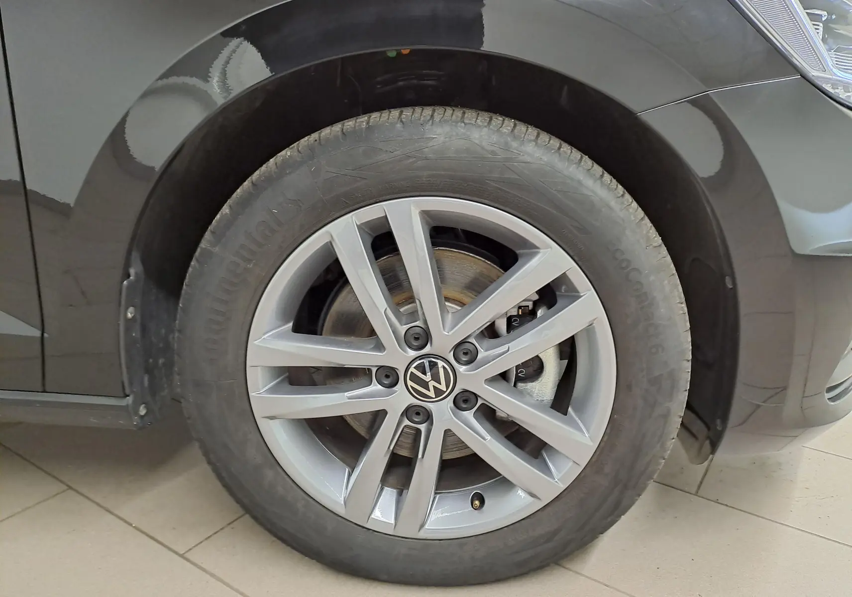 Gros plan sur la roue avant droite d’un Volkswagen Touran noir intense nacré avec jante alliage 7 branches.