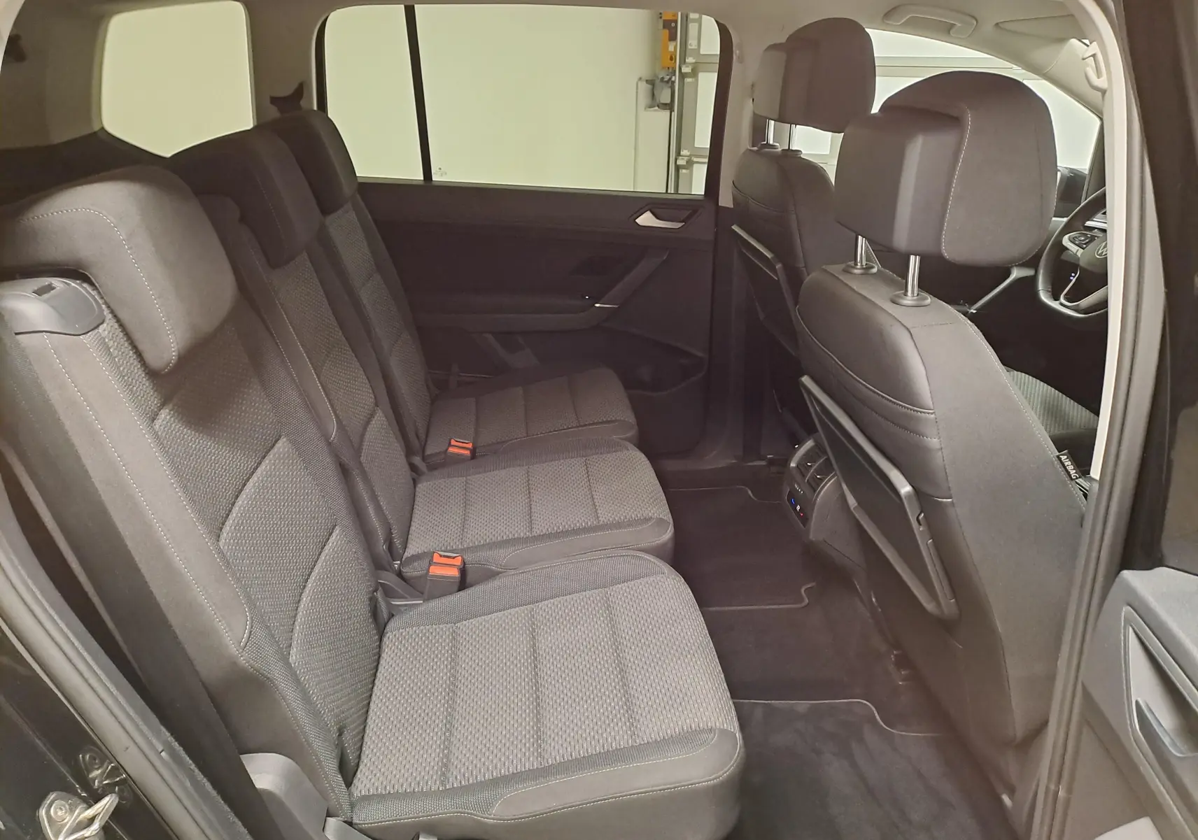 Vue intérieure côté gauche des sièges arrière en tissu gris du Volkswagen Touran 2025, version 7 places.