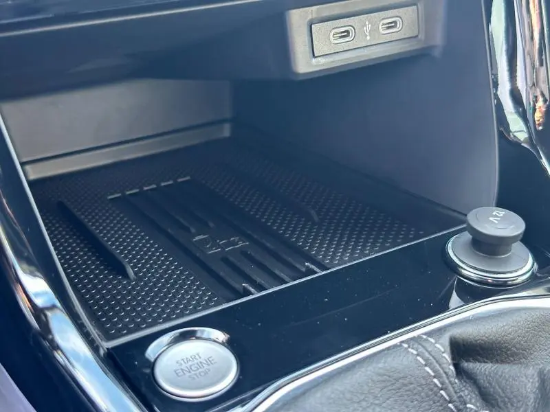 Gros plan sur la console centrale du Volkswagen T-Cross 2025, avec bouton Start/Stop et prise 12V, finition noire brillante.