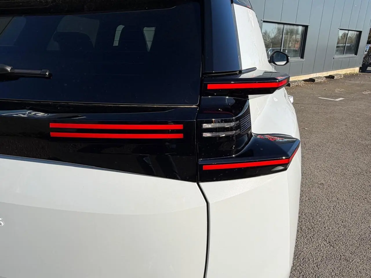 Vue arrière droite du Citroën C5 Aircross blanc Okenite avec feux arrière LED horizontaux rouges et toit noir brillant.