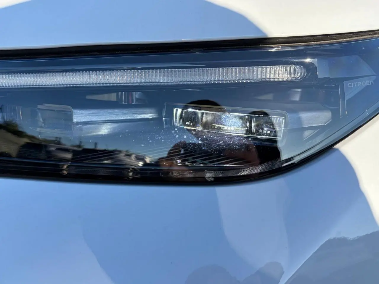 Gros plan sur le phare avant droit du Citroën C5 Aircross blanc Okenite, mettant en valeur les détails LED et la signature lumineuse.