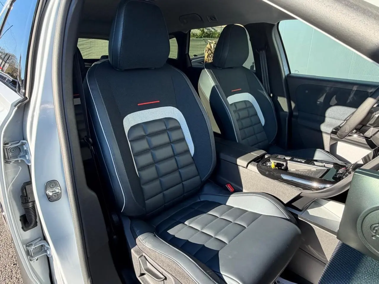 Vue intérieure des sièges avant noirs et gris du Citroën C5 Aircross blanc, avec console centrale et portière côté droit visibles.