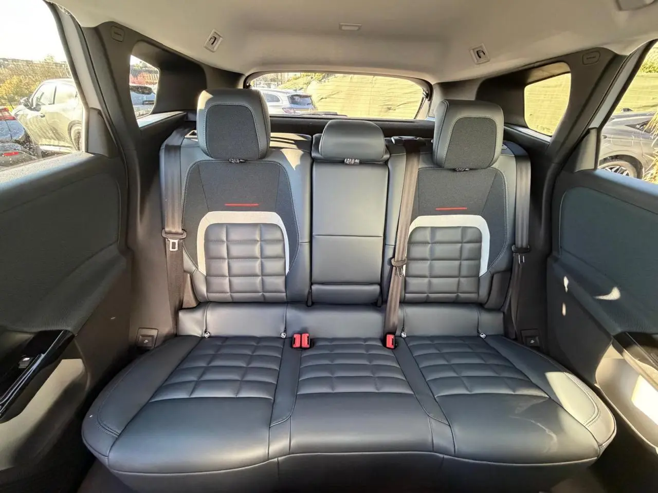 Vue arrière intérieure du Citroën C5 Aircross 2026 montrant la banquette arrière en cuir noir avec inserts tissu et ceintures de sécurité.