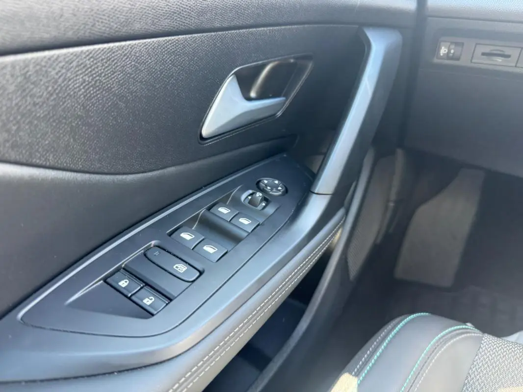 Gros plan sur la commande des vitres électriques côté conducteur de la Peugeot 308 Hybrid 136 e-DCS6 Allure noire de 2024.