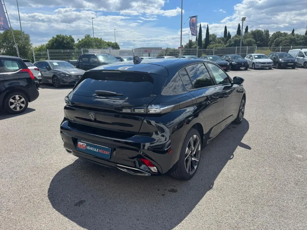 Peugeot 308 Hybrid noir vue en 3/4 arrière droit, avec jantes alliage 17 pouces et vitres teintées.