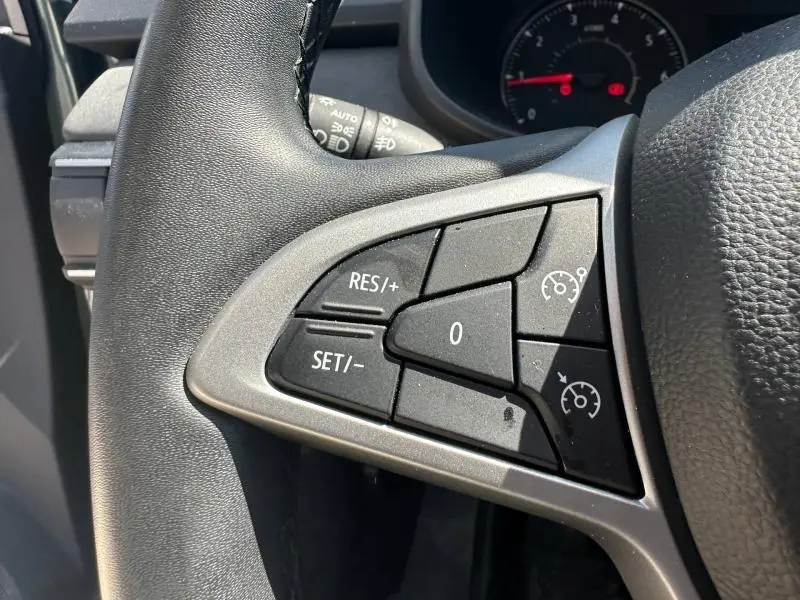 Gros plan sur les commandes de régulateur de vitesse au volant noir de la Dacia Sandero 2025.