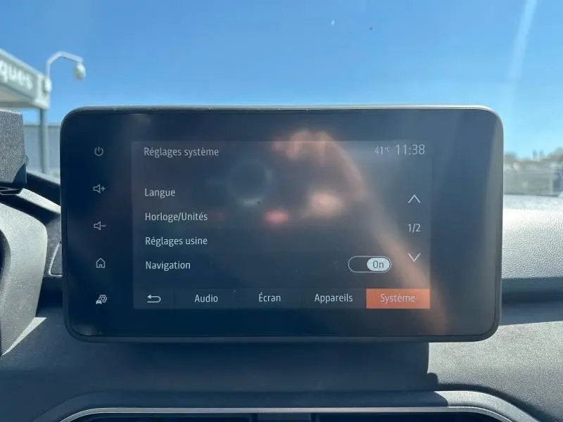 Écran tactile central du tableau de bord de la Dacia Sandero 2025, affichant les réglages système sous lumière naturelle.