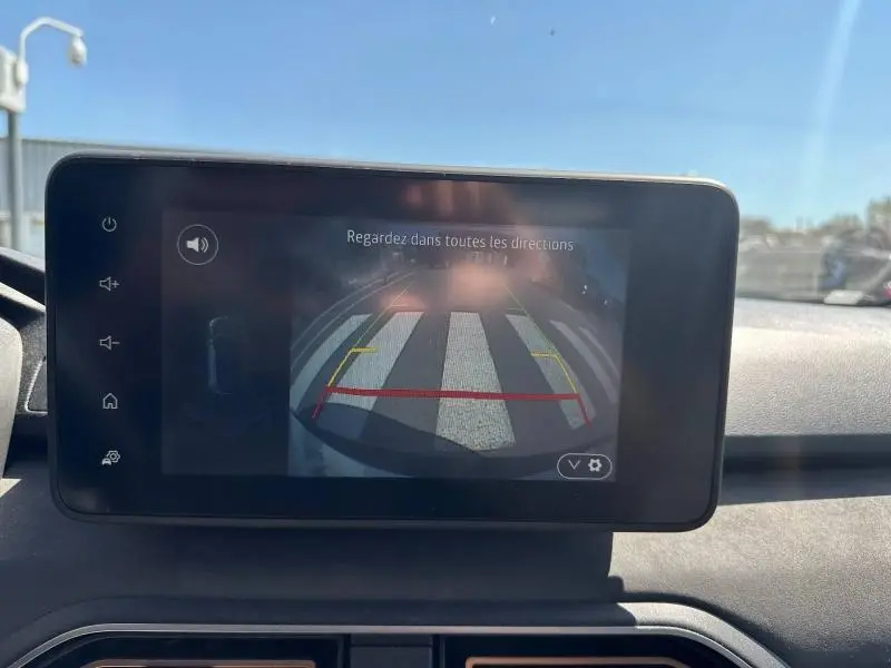 Écran tactile intérieur montrant la caméra de recul avec vue arrière sur un passage piéton en plein jour.