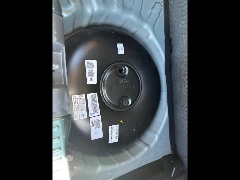 Vue rapprochée du réservoir GPL rond noir dans le coffre d'une Dacia Sandero 2025, entouré de la structure métallique grise.