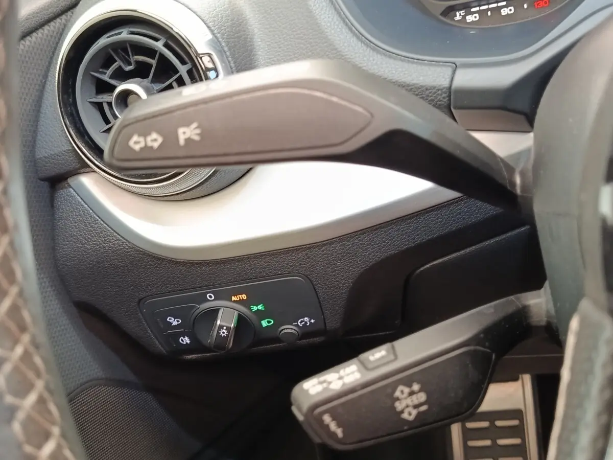 Détail intérieur côté gauche du tableau de bord noir d’un Audi Q2 35 TFSI 2021 avec commandes d’éclairage et aérateur rond.
