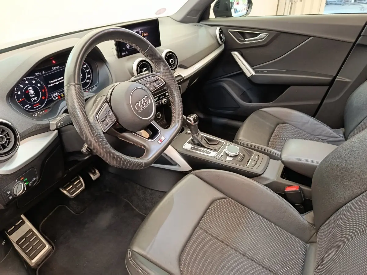 Vue intérieure côté conducteur de l'Audi Q2 35 TFSI S Line 2021, avec volant cuir et tableau de bord numérique.
