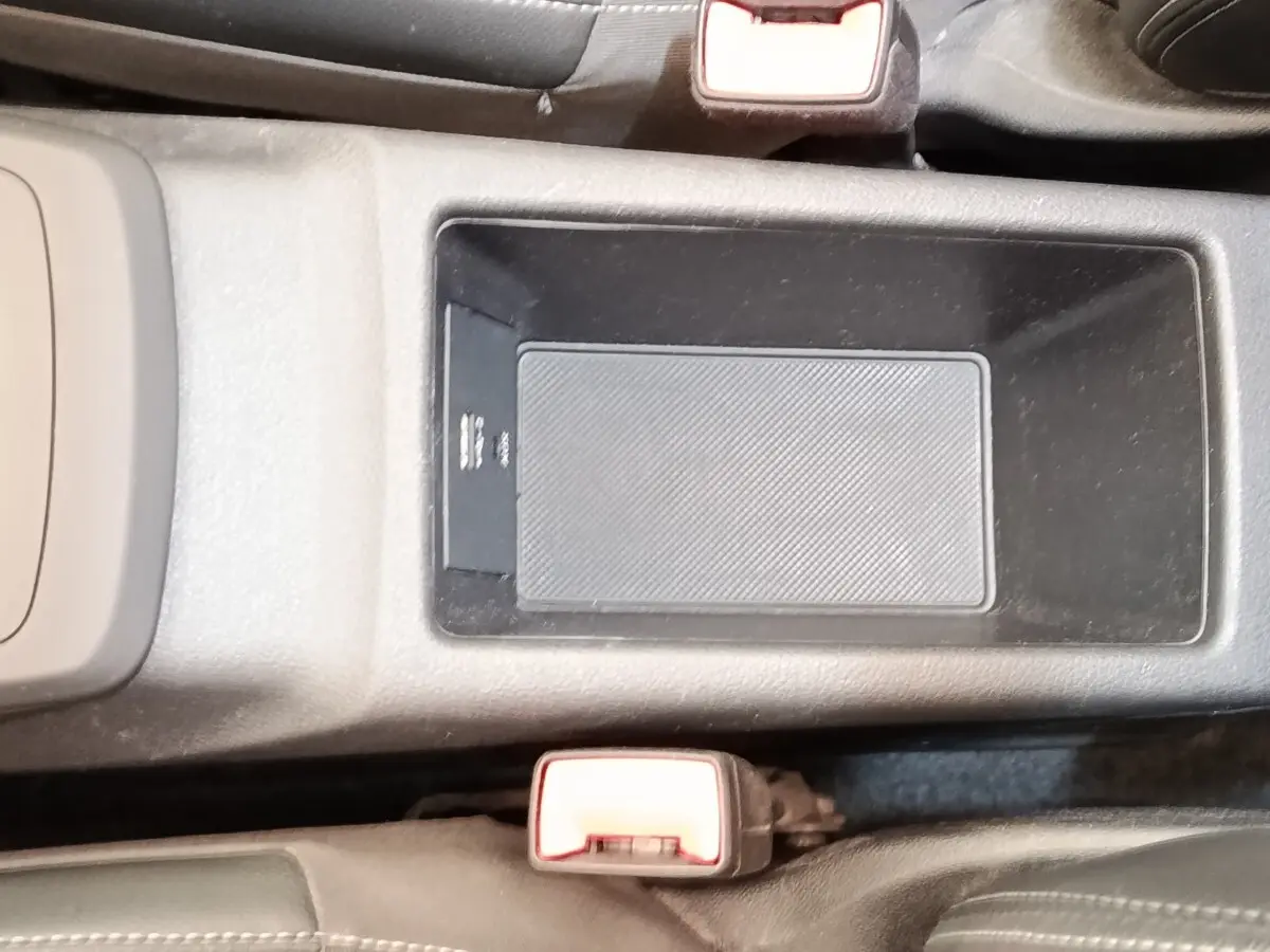 Vue rapprochée de la console centrale noire de l’Audi Q2 35 TFSI 150 S Tronic S Line avec rangement et boucle de ceinture rouge.