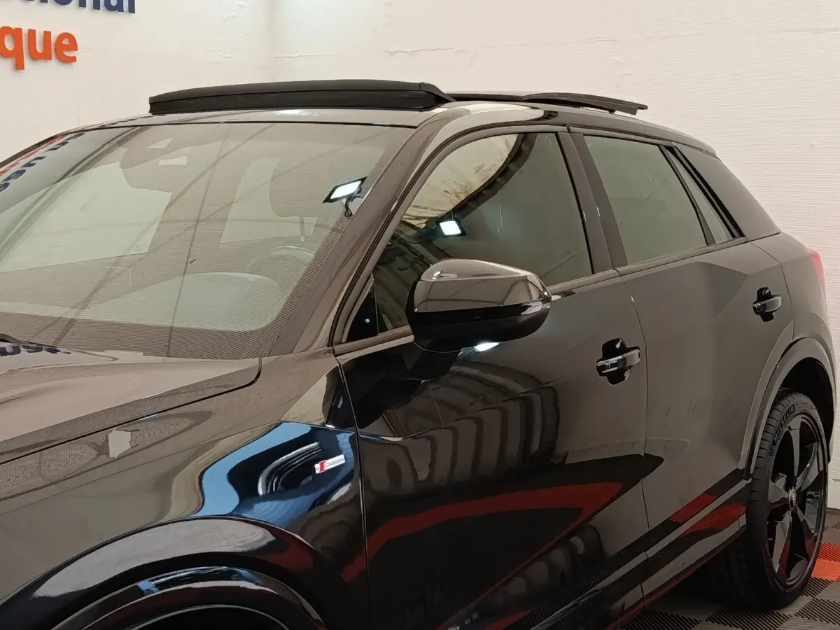 Vue de côté droit d’un Audi Q2 noir S Line 35 TFSI avec toit ouvrant et jantes noires distinctives.