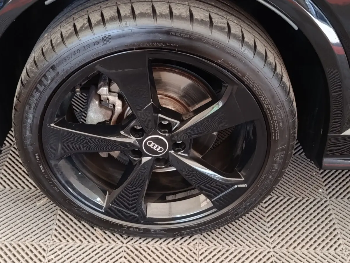 Gros plan sur la roue avant droite noire d’un Audi Q2 35 TFSI S Line, avec jante en alliage noir brillant.
