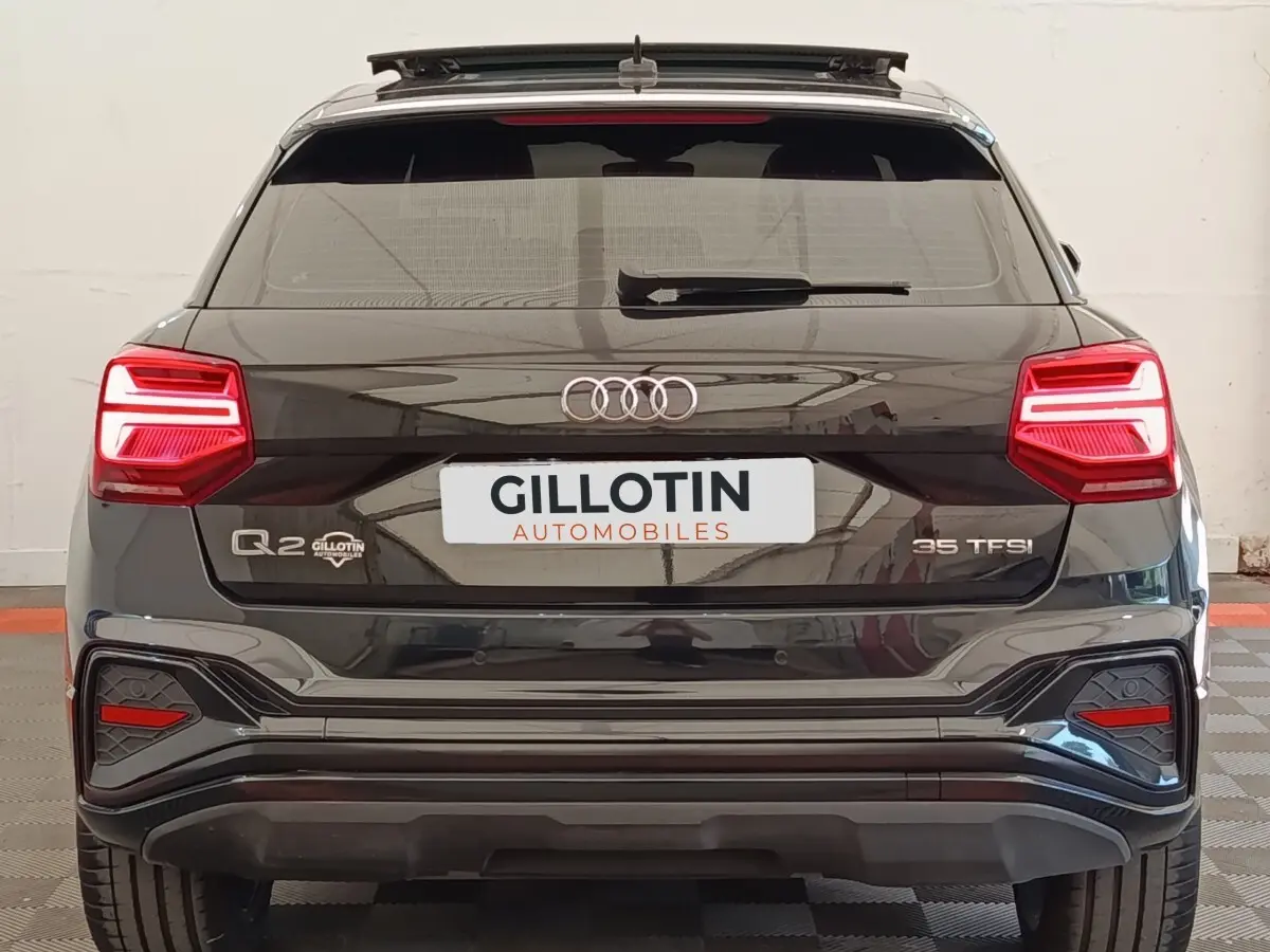 Vue arrière d’un Audi Q2 noir 35 TFSI avec feux LED et logo distinctif sur un sol à damier.