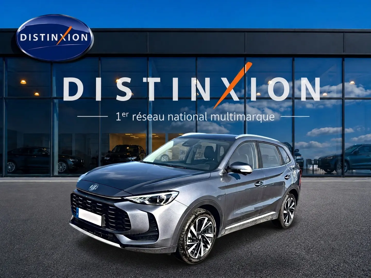 MG ZS 1.5 hybrid gris en 3/4 avant droit, avec calandre noire et jantes alliage 18 pouces visibles.