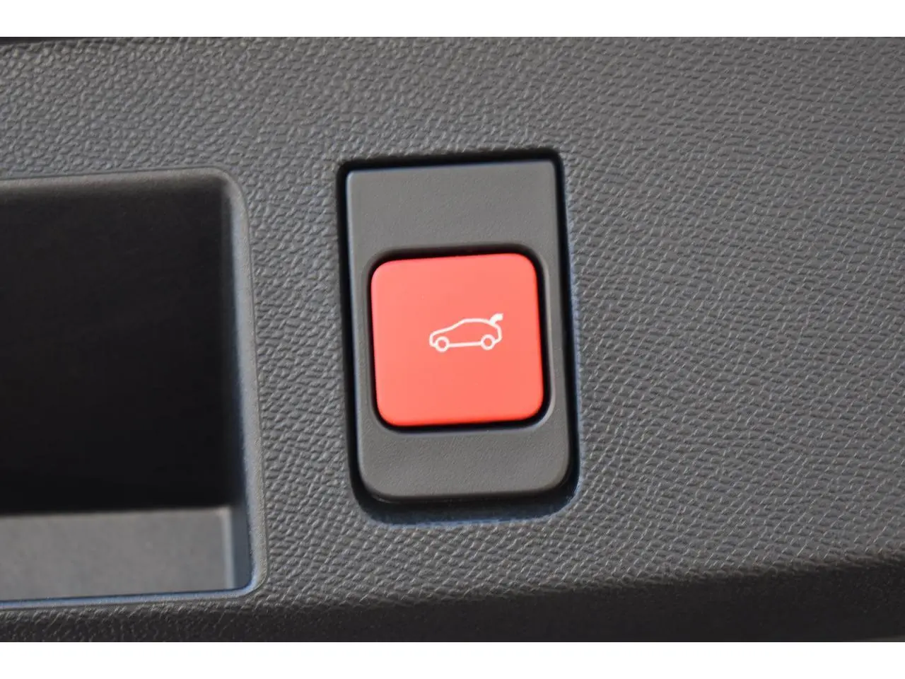 Gros plan sur le bouton rouge d'ouverture du hayon motorisé du Citroën C5 Aircross blanc hybride 2026.