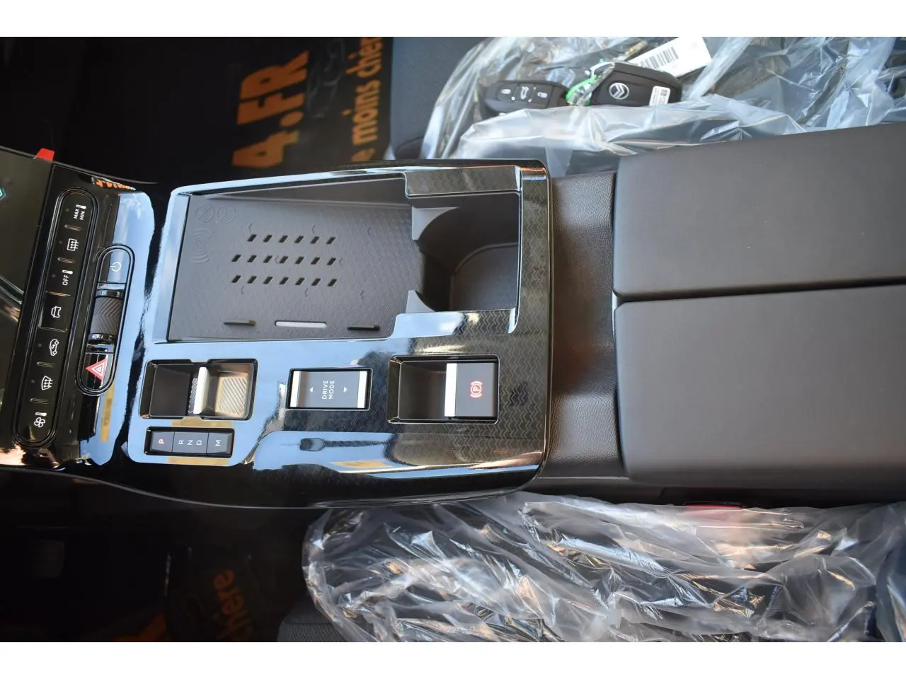 Vue rapprochée de la console centrale noire brillante du Citroën C5 Aircross hybride avec commandes de boîte auto et accoudoir.
