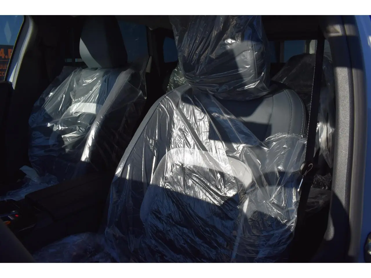 Vue intérieure rapprochée des sièges avant protégés par des housses plastiques dans un Citroën C5 Aircross blanc.