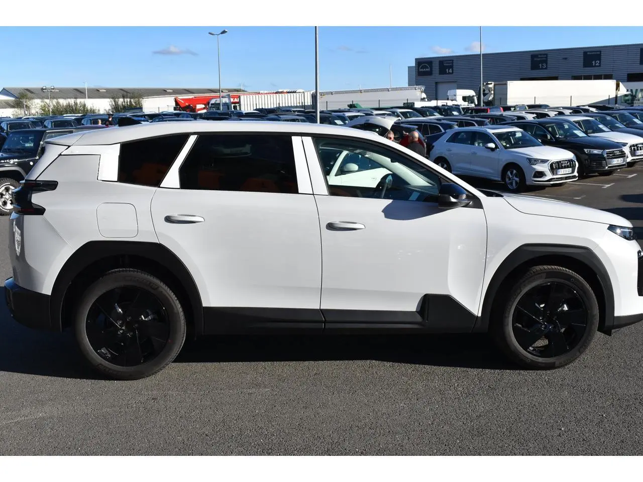 Profil droit d'un Citroën C5 Aircross blanc 2026 avec jantes noires et vitres arrière surteintées sur parking.