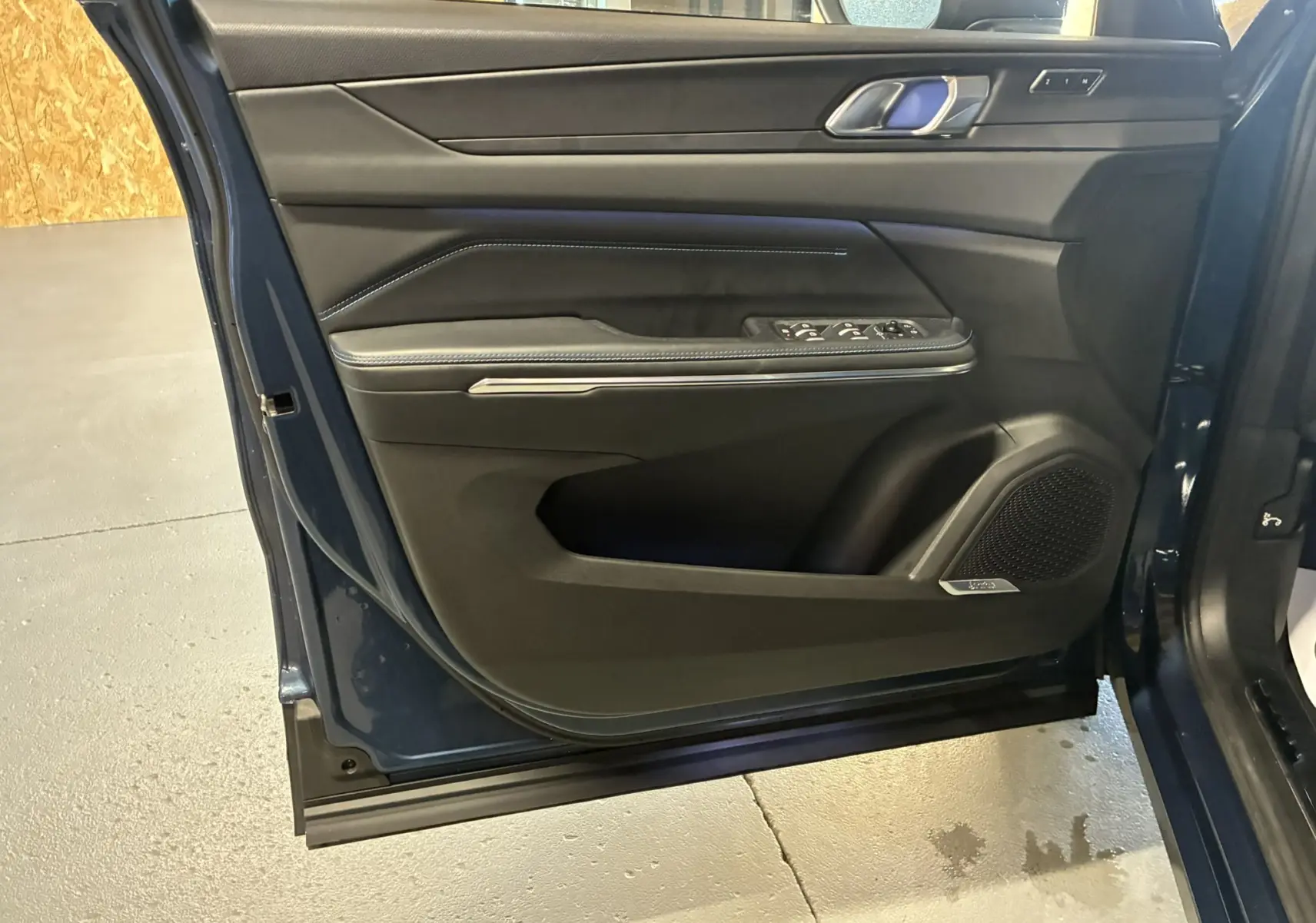 Vue rapprochée de la porte avant gauche bleu du LYNK & CO 01, avec commandes de vitres et haut-parleur intégré.