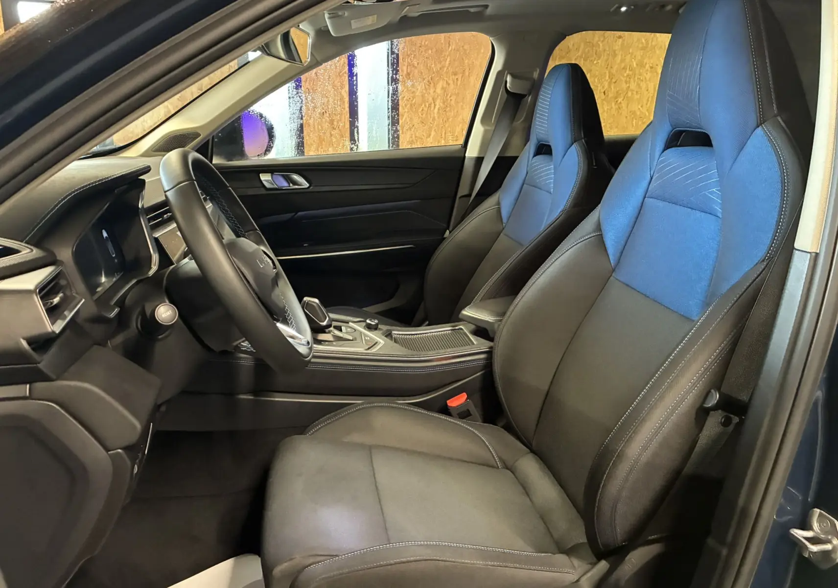 Vue intérieure côté conducteur du LYNK & CO 01 2023 avec sièges bi-matière noir et bleu et tableau de bord moderne.