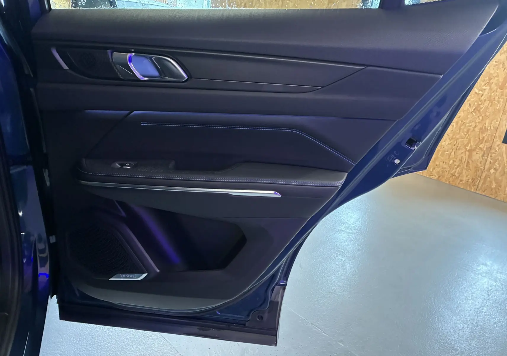 Vue rapprochée de la porte arrière droite bleu foncé du LYNK & CO 01 avec garniture noire et surpiqûres bleues.