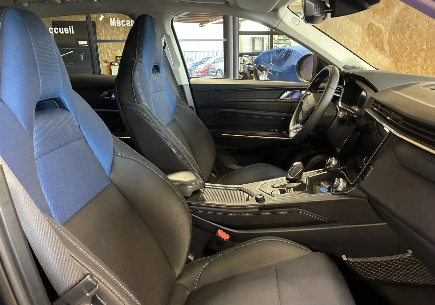 Intérieur avant du Lynk & Co 01 2023, sièges cuir noir et tissu bleu, tableau de bord et console centrale visibles côté conducteur.