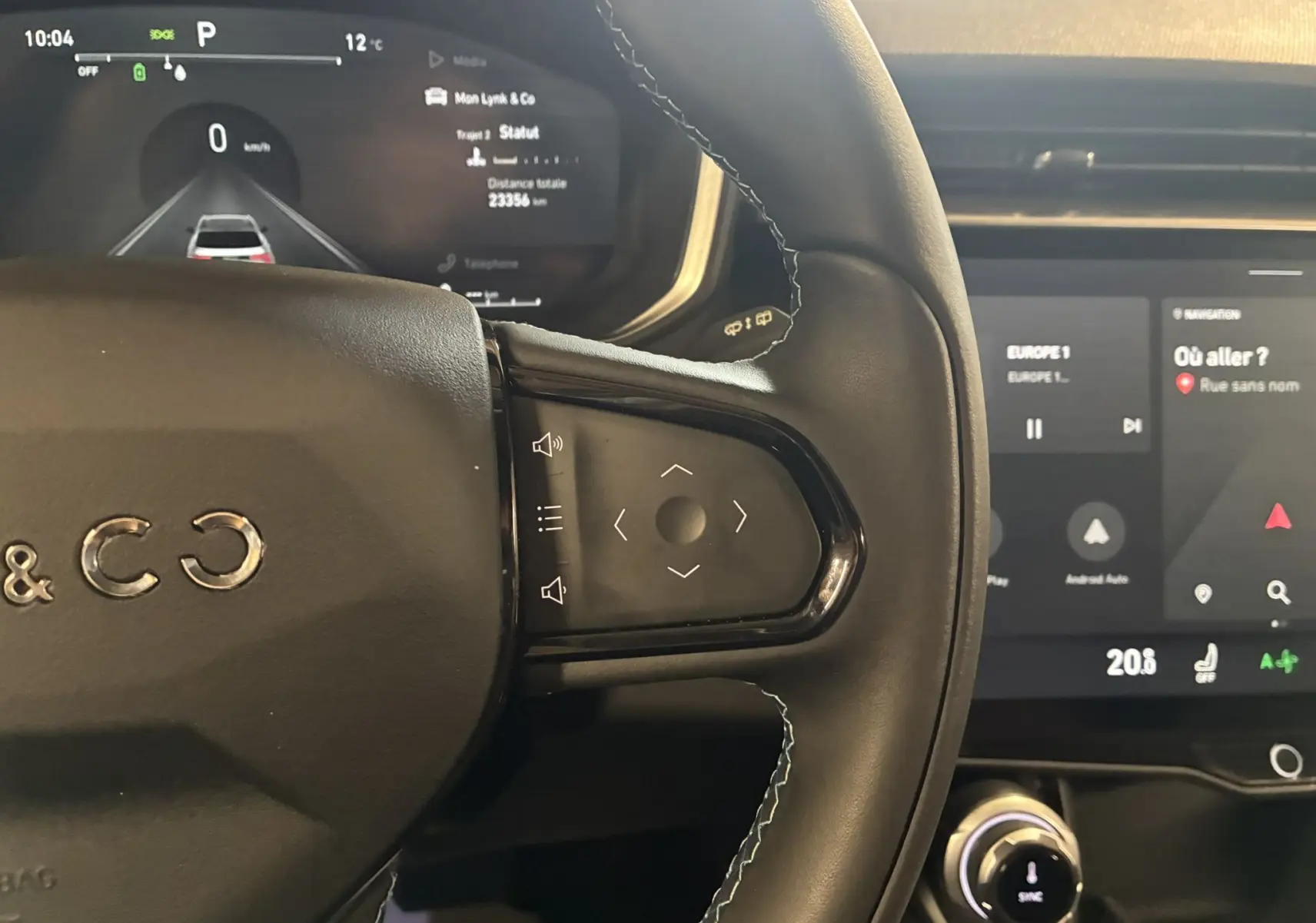 Vue rapprochée du volant noir du Lynk & Co 01 2023 avec commandes intégrées et tableau de bord numérique allumé.