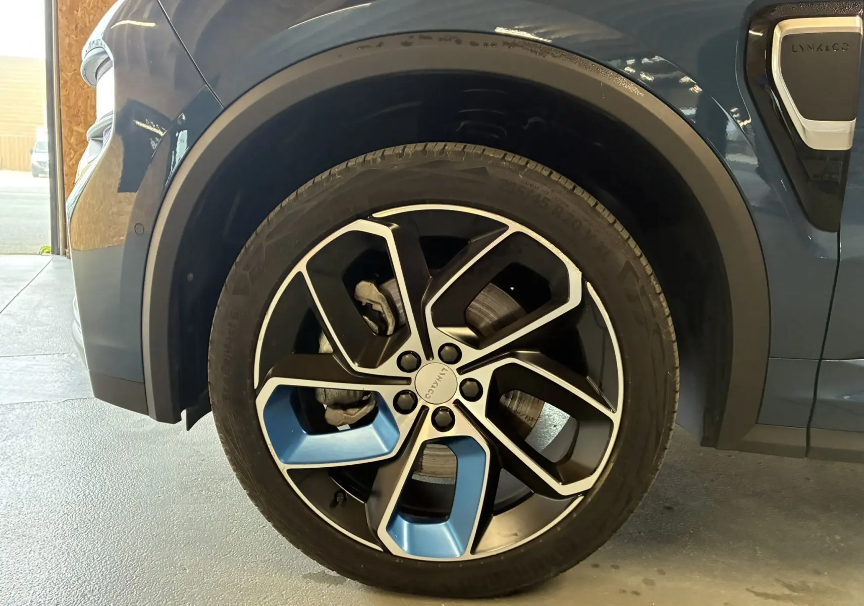 Gros plan sur la roue avant gauche bleu et noir du LYNK & CO 01 hybride rechargeable 2023 avec jante au design moderne.