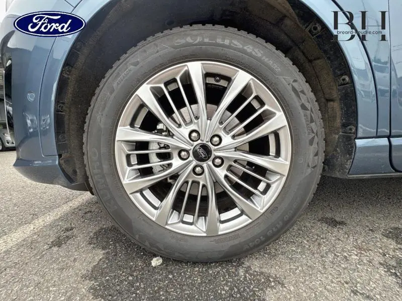 Gros plan sur la roue avant gauche en jante alu du Ford Kuga bleu azur métallisé de 2022.