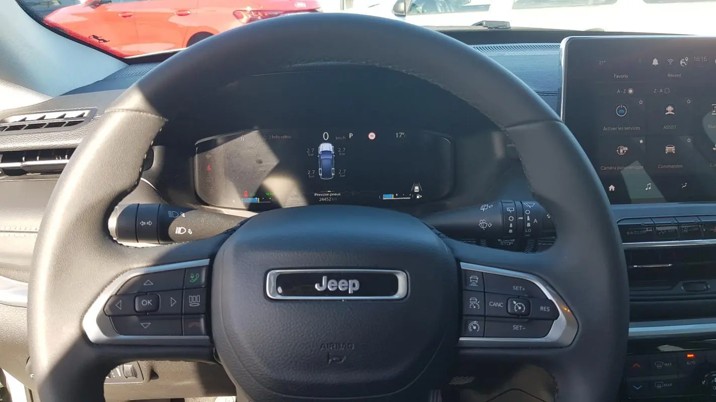 Vue centrée sur le volant noir du Jeep Compass 2024 avec tableau de bord numérique et écran tactile à droite.