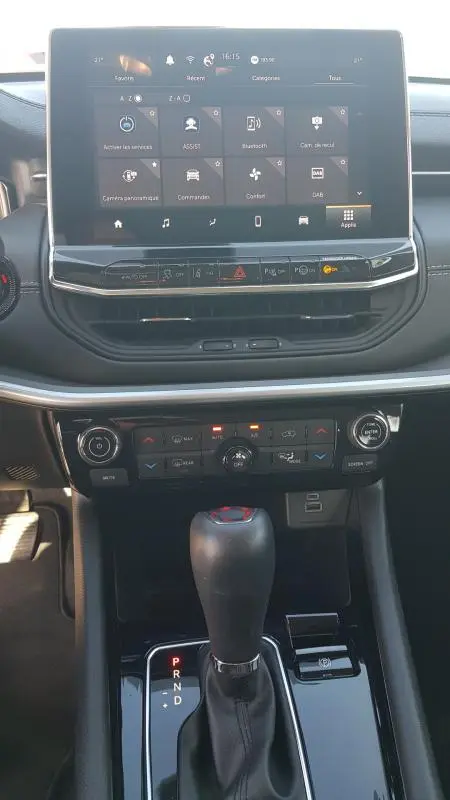 Vue rapprochée du tableau de bord et levier de vitesse du Jeep Compass blanc 2024 avec écran tactile et commandes climatisation.