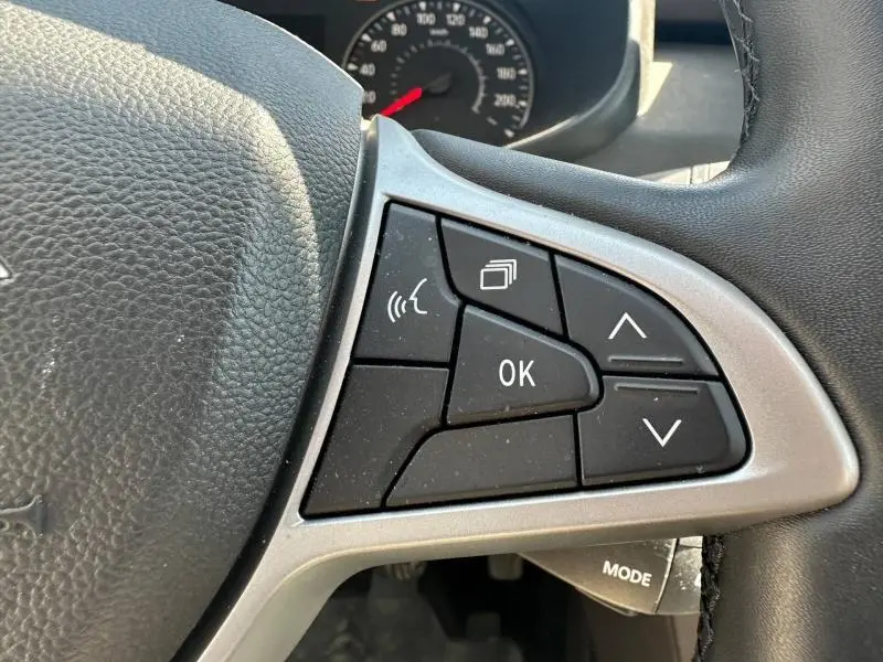 Gros plan sur les commandes multifonctions à droite du volant noir du Dacia Sandero 2025, boutons noirs et contour argenté.