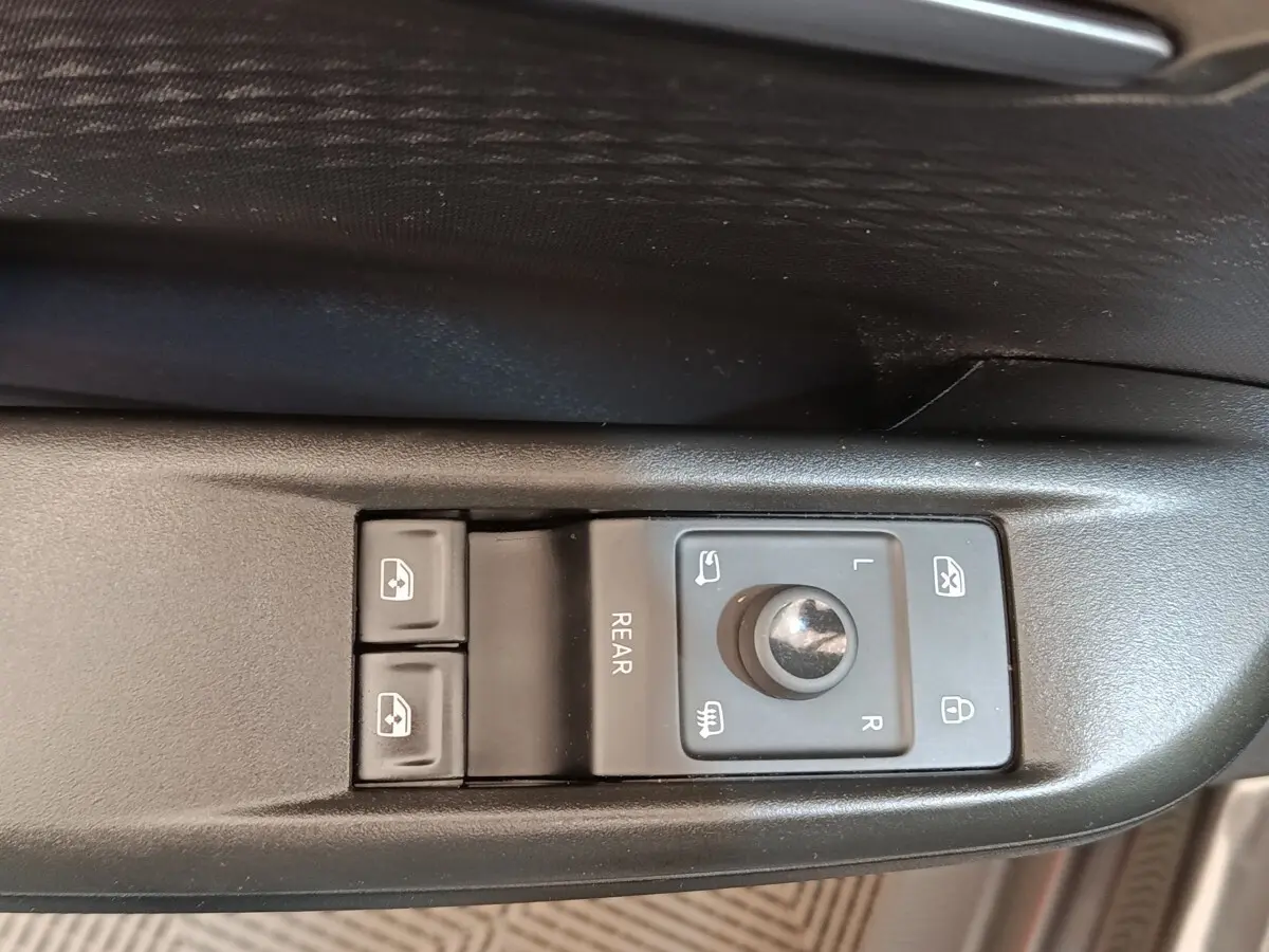 Gros plan sur les commandes de réglage des rétroviseurs et des vitres côté conducteur d'une CUPRA BORN gris foncé.