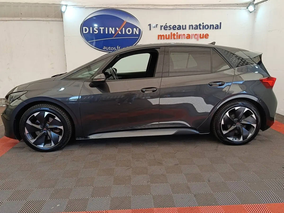 Vue de profil côté gauche d'une CUPRA BORN 230ch gris foncé avec jantes noires et logo rouge au centre.