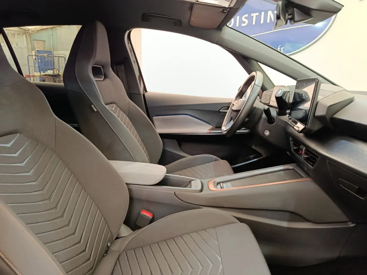Vue intérieure côté droit de la CUPRA Born 230ch gris foncé, avec sièges sport et écran tactile central vertical.