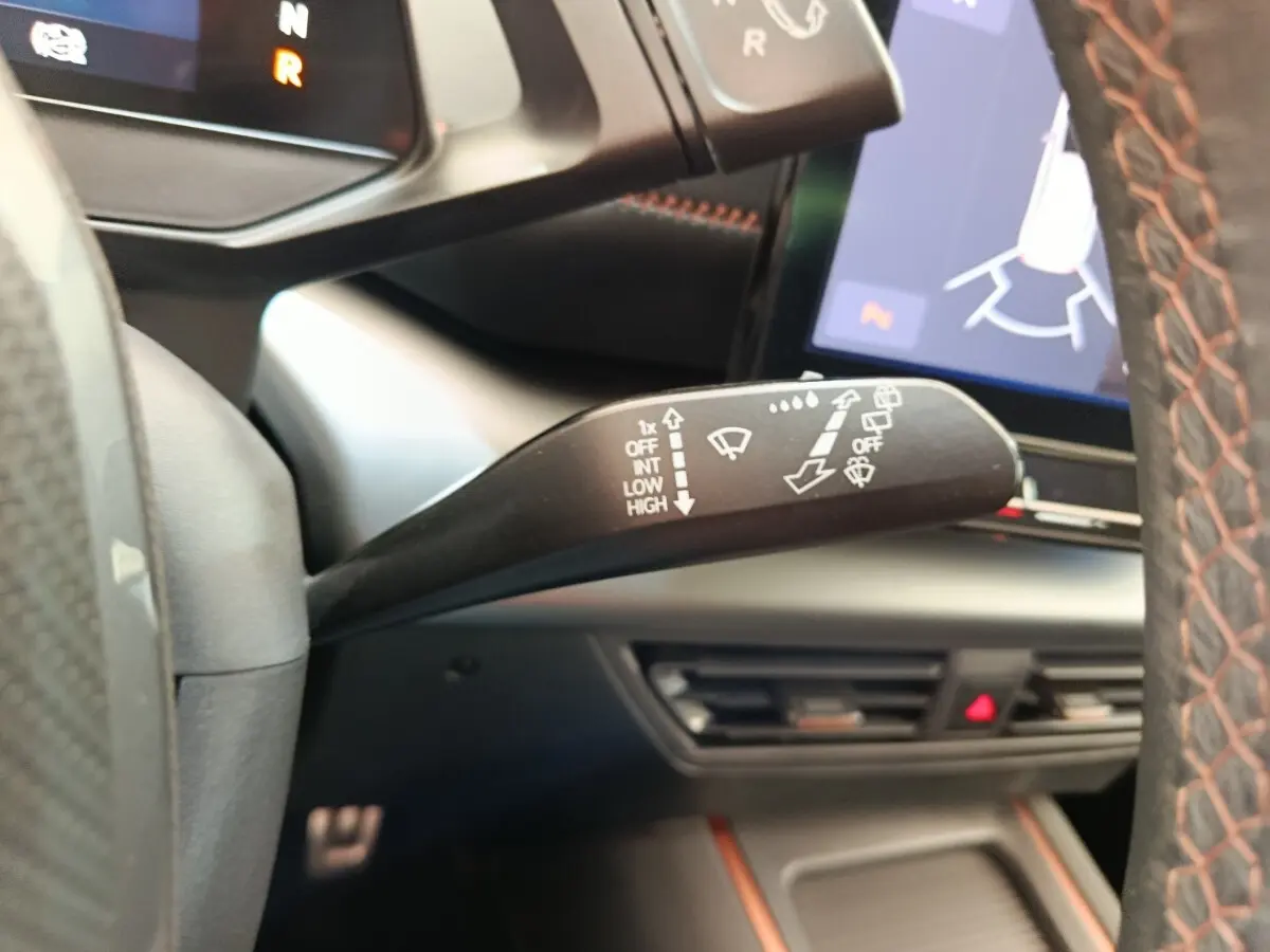 Gros plan sur la commande d’essuie-glace à gauche du volant dans l’habitacle gris foncé du CUPRA Born 230ch 2023.