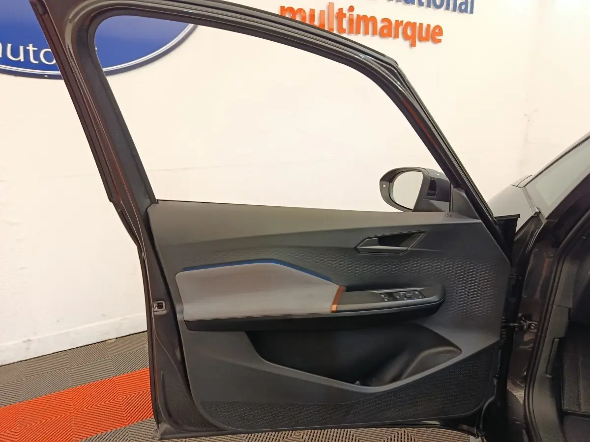Vue intérieure de la porte avant gauche gris foncé du CUPRA BORN 230ch avec détails de commandes et habillage texturé.