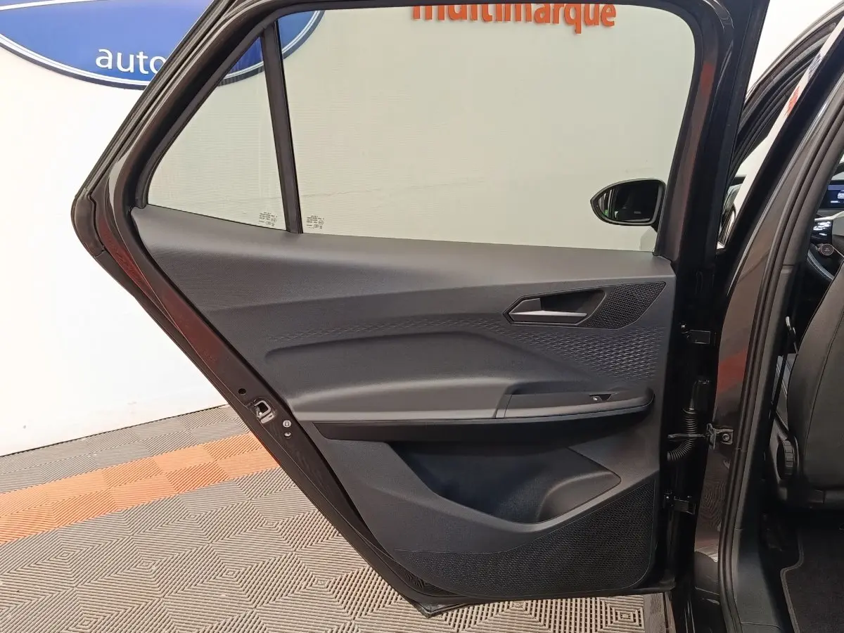 Vue intérieure de la porte arrière gauche gris foncé du CUPRA BORN 230ch avec détails des commandes et haut-parleur intégré.