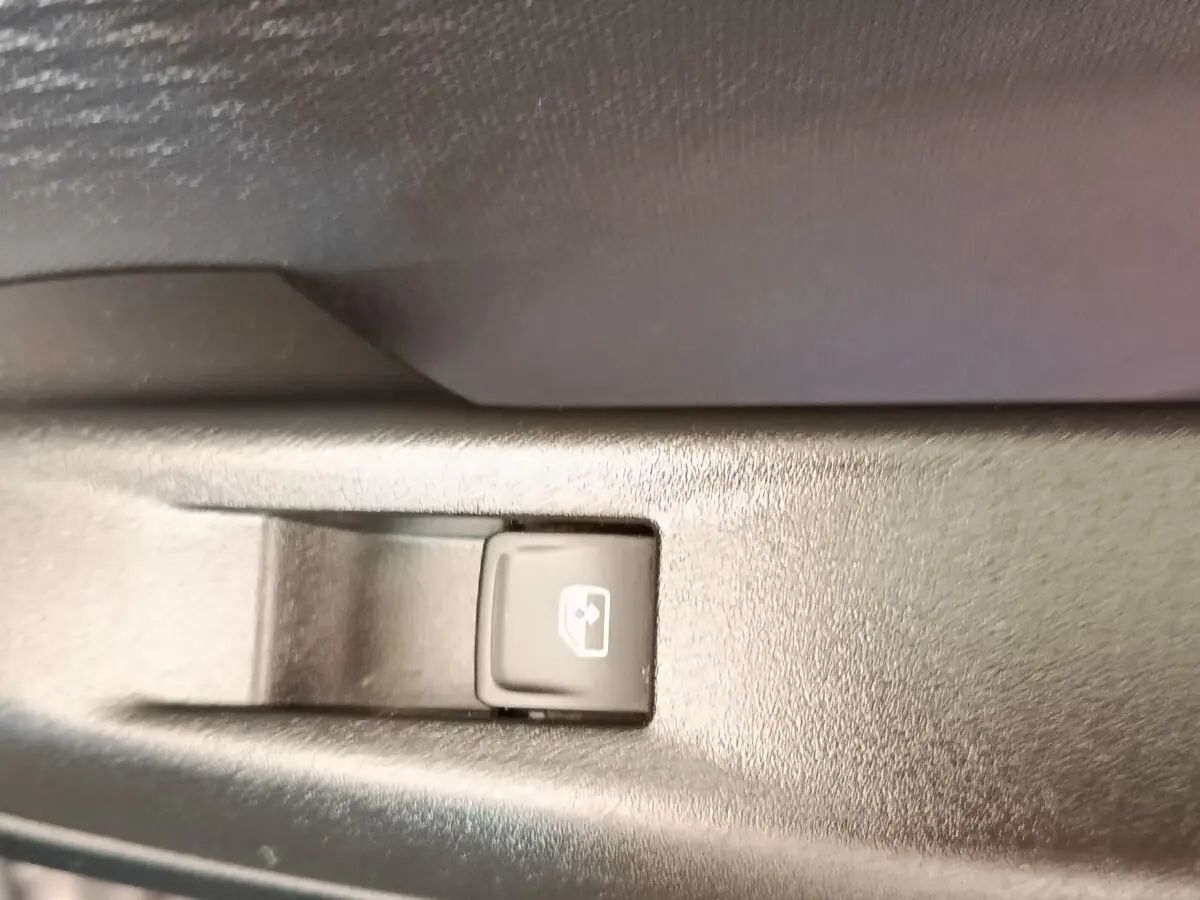 Bouton de commande de lève-vitre électrique sur panneau intérieur noir, détail du CUPRA Born 230ch gris foncé 2023.