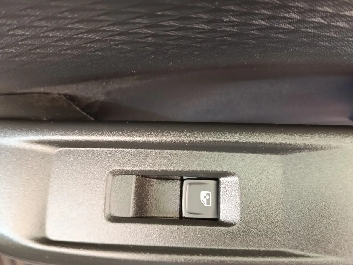 Gros plan sur le bouton de commande de lève-vitre électrique, intérieur noir du côté gauche du CUPRA Born gris foncé.