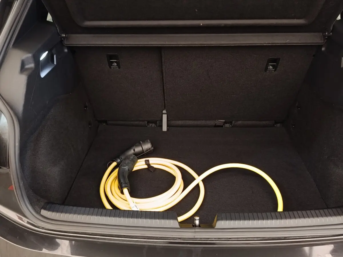 Coffre ouvert d'une CUPRA Born gris foncé avec câble de charge électrique jaune enroulé à l'intérieur.