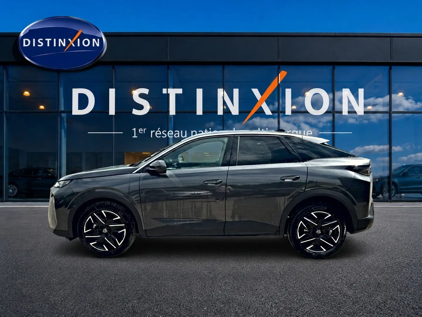 Peugeot 3008 gris titane en profil droit devant une vitrine avec logo Distinxion, jantes alu noires et blanches.