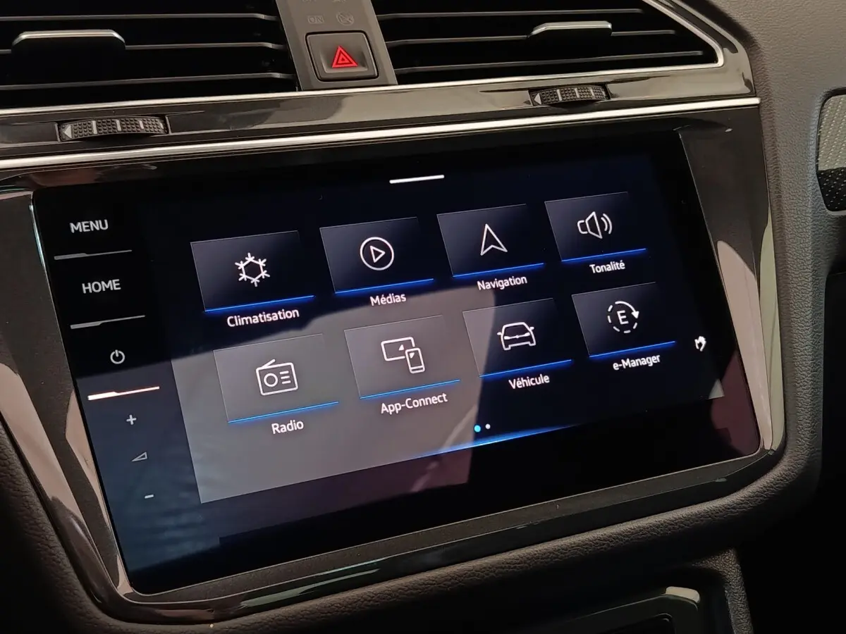Écran tactile central du tableau de bord du Volkswagen Tiguan blanc 2023 affichant les menus climatisation, médias et navigation.